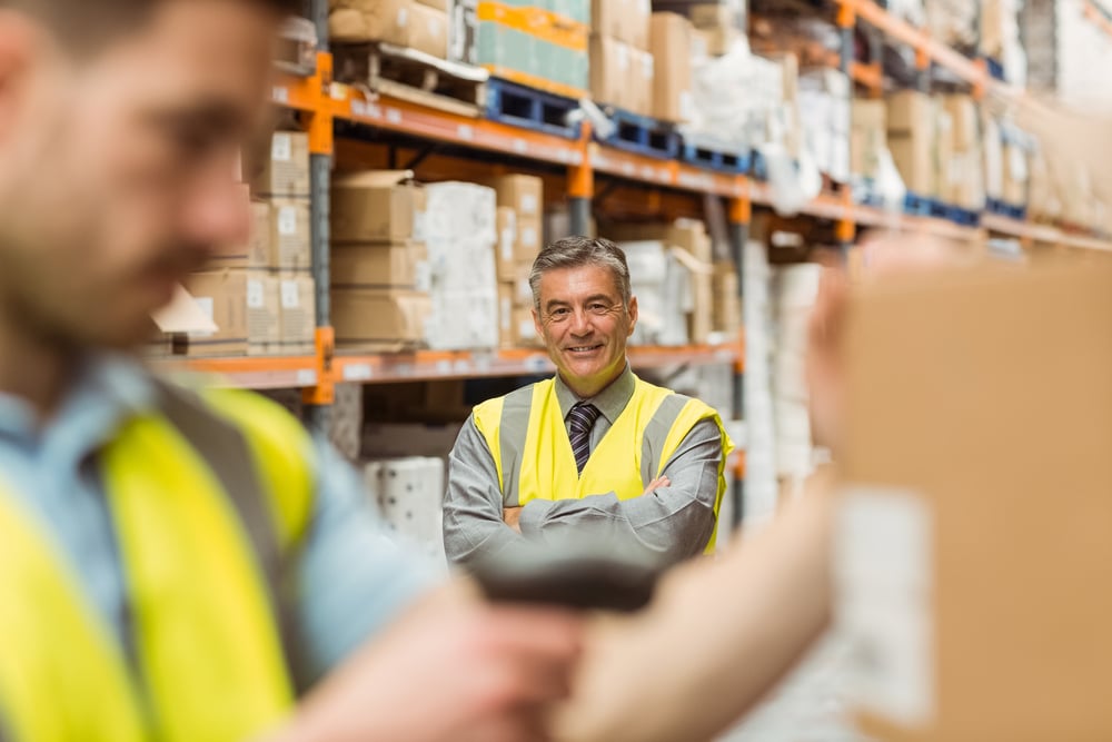 Warehouse worker scanning barcode on box in a large warehouse